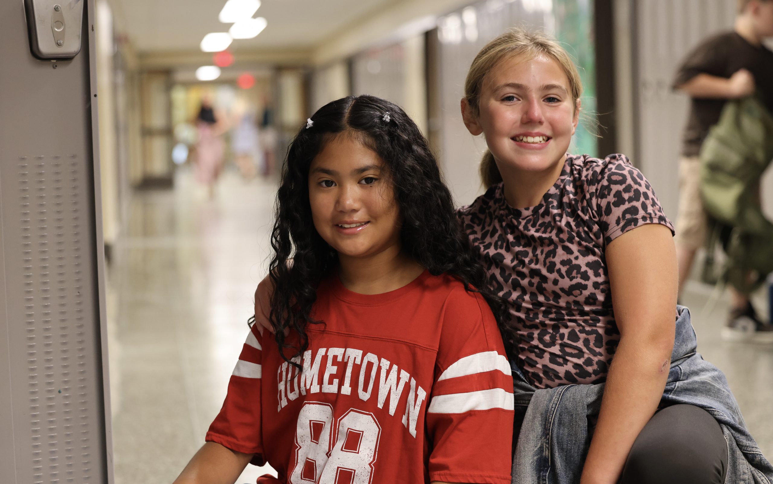 two students pose for photo near lockers