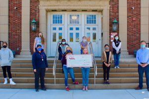 students hold a check from stewart's shops