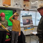 students in hard hats talk with State Trooper