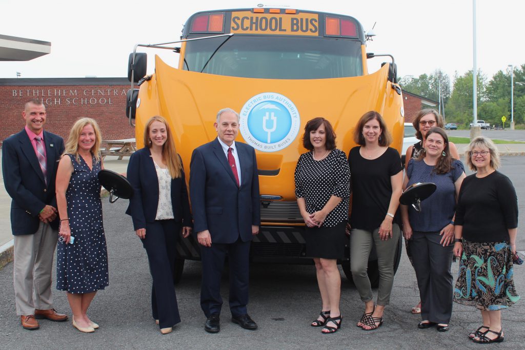 group of people pose with electric bus