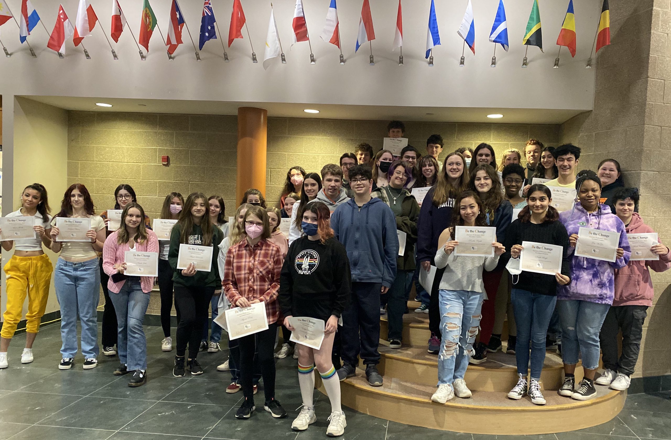 group of students pose for photo in high school foyer