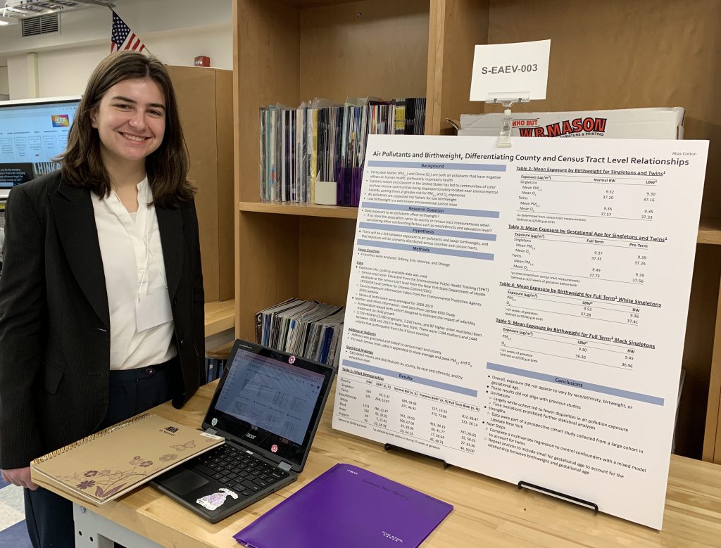 student stands next to display board