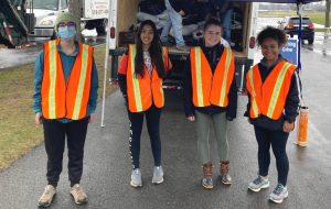 Students wearing orange vests in front of collection truck