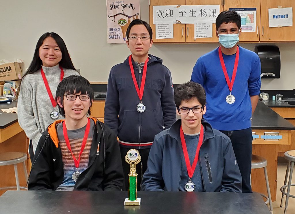 five students with medals and trophy