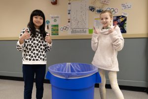 Fourth grade students Yuzuki Izumi and Grace Leddy give thumbs up while standing near recycling area at Elsmere Elementary