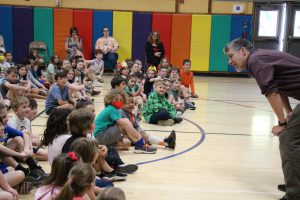 person leaning over talking with students in colorful gym