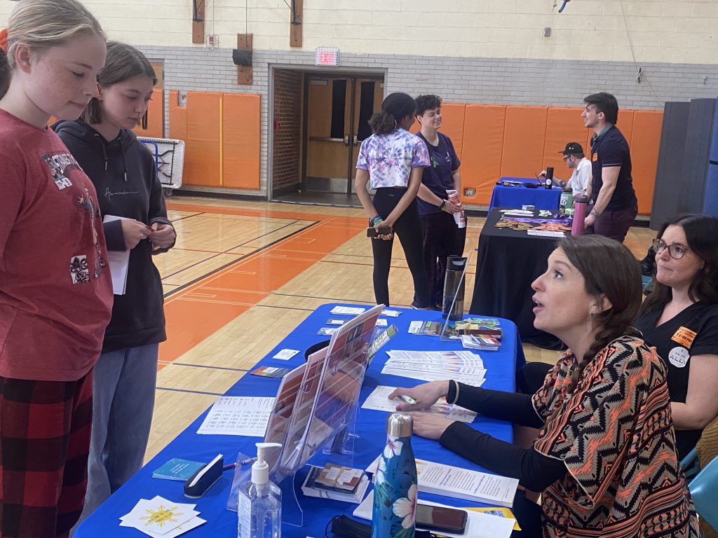 person at table talking to students