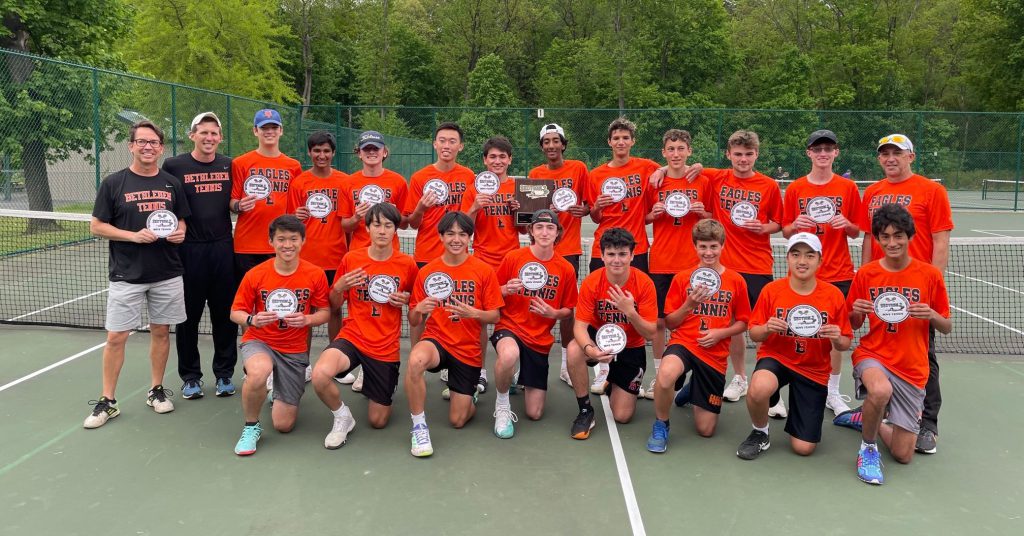 team members in orange shirts pose for photo