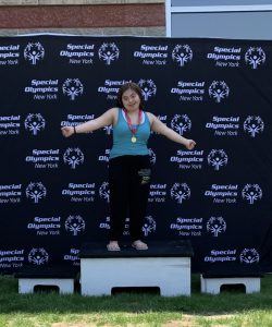 student stands on podium with medal