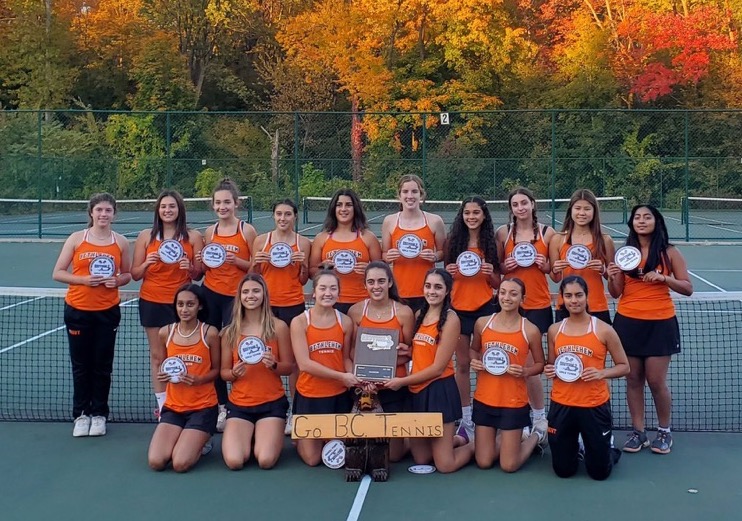 team in orange and black uniforms on tennis court