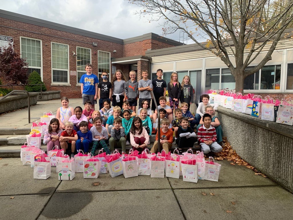 Slingerlands students pose outside of school with chemo care bags they assembled for patients going through chemotherapy for breast cancer.