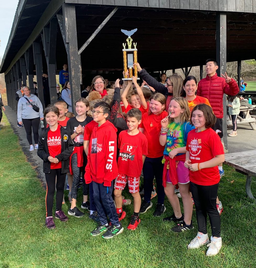 students in red shirts holding trophy