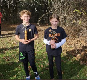 two students in black shirts holding trophies