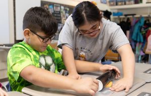 High school student with BC Barkery shows elementary student how to roll dough when making dog treats.