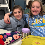 two students smiling with lunch bags