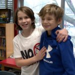 Two students embrace and smile after being on opposite debate teams.