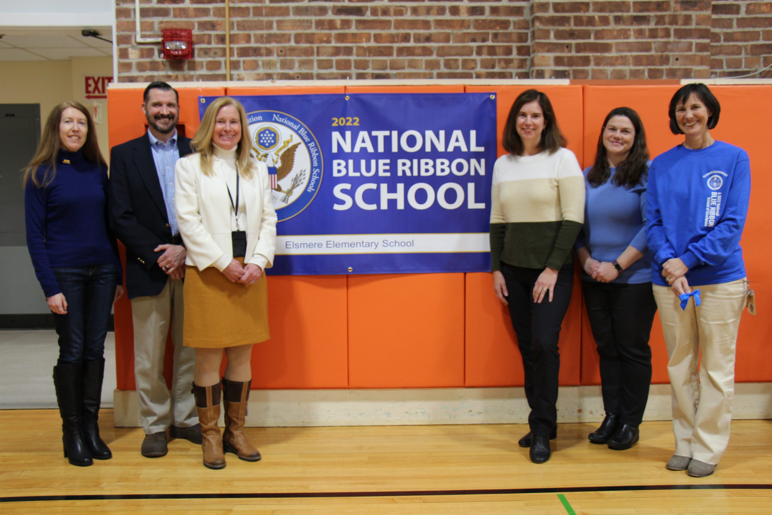 group of people stand next to blue banner