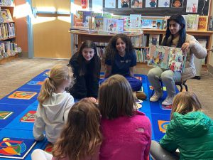 student reads book to other students