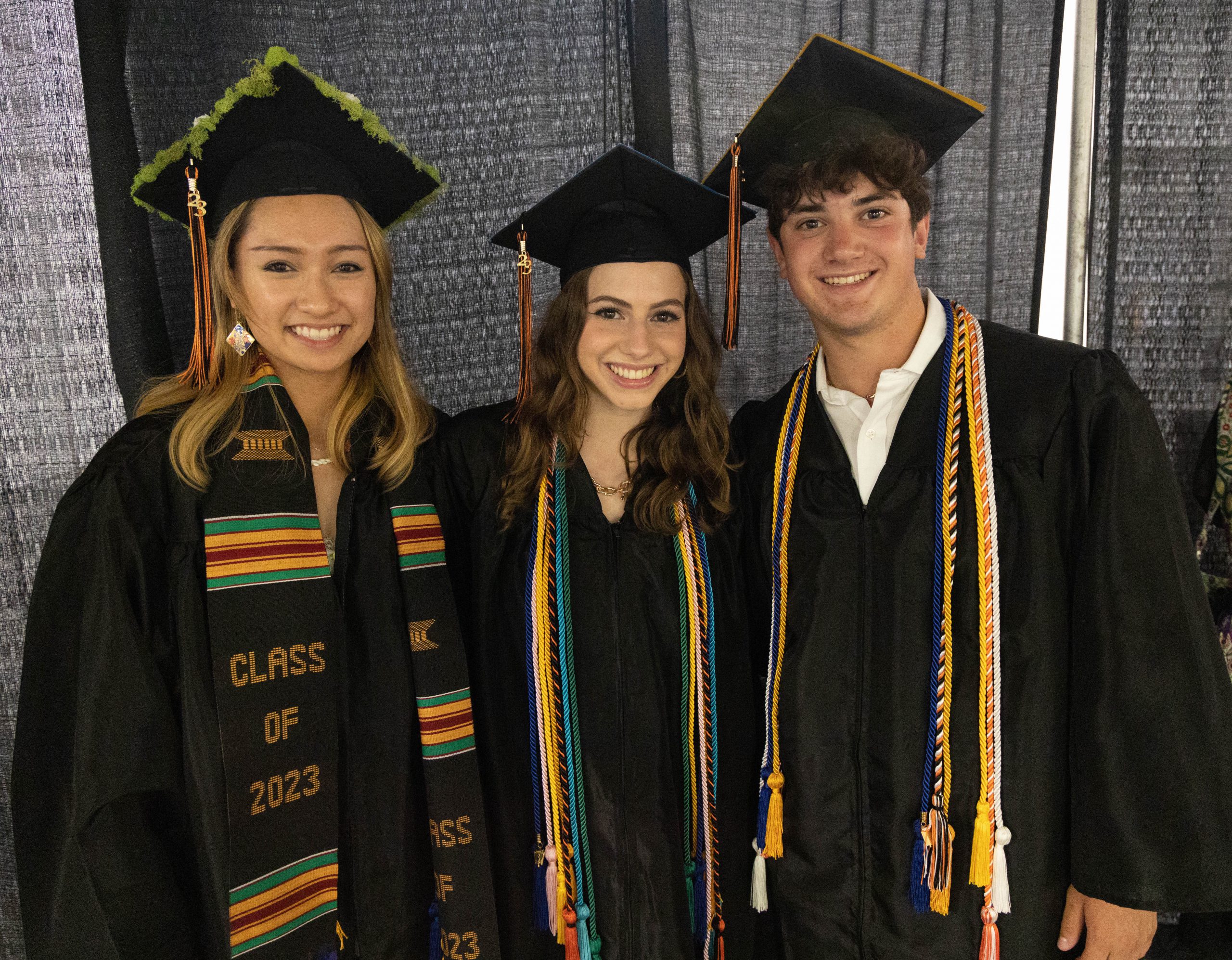 three students in caps and gowns