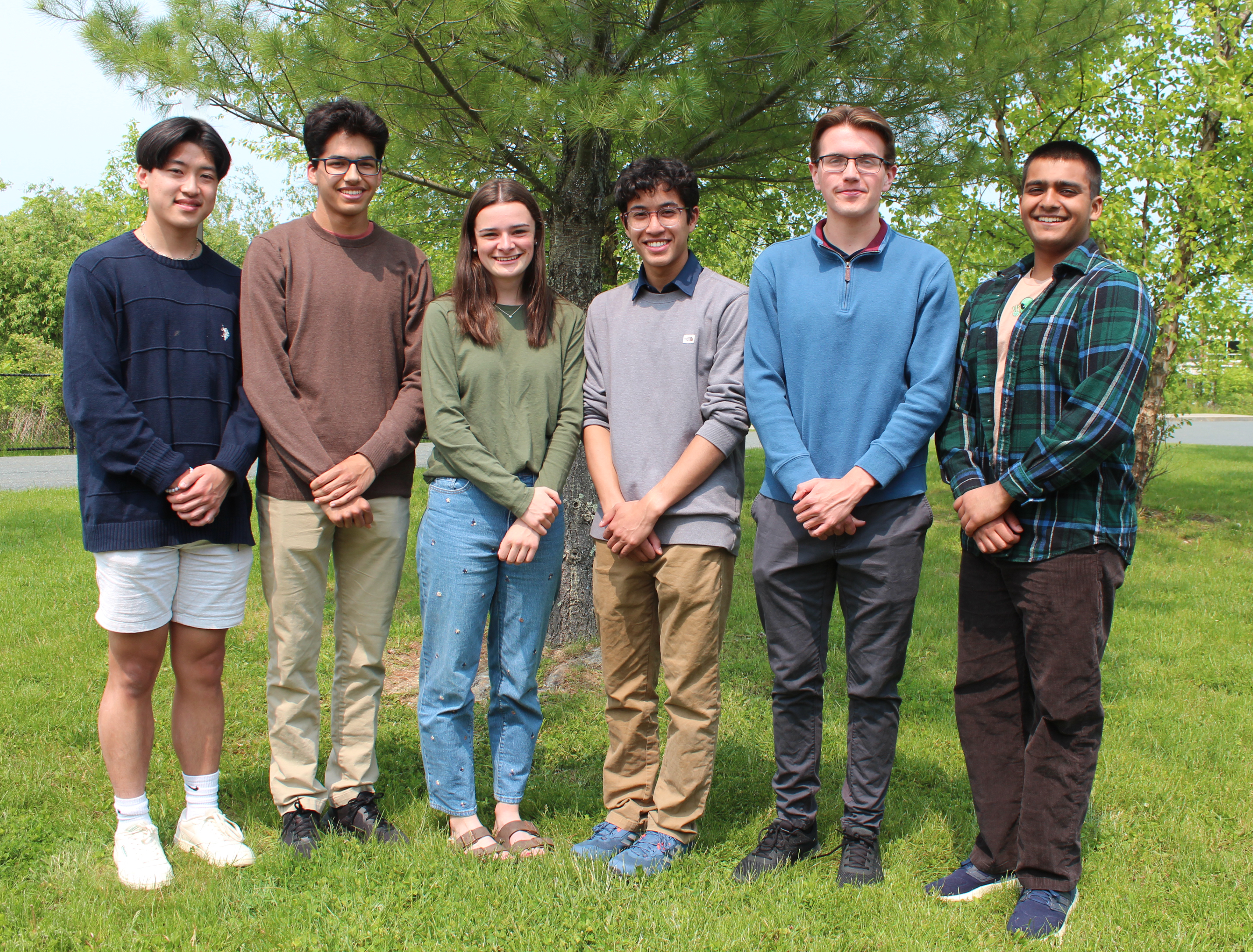 six students pose for photo in front of tree