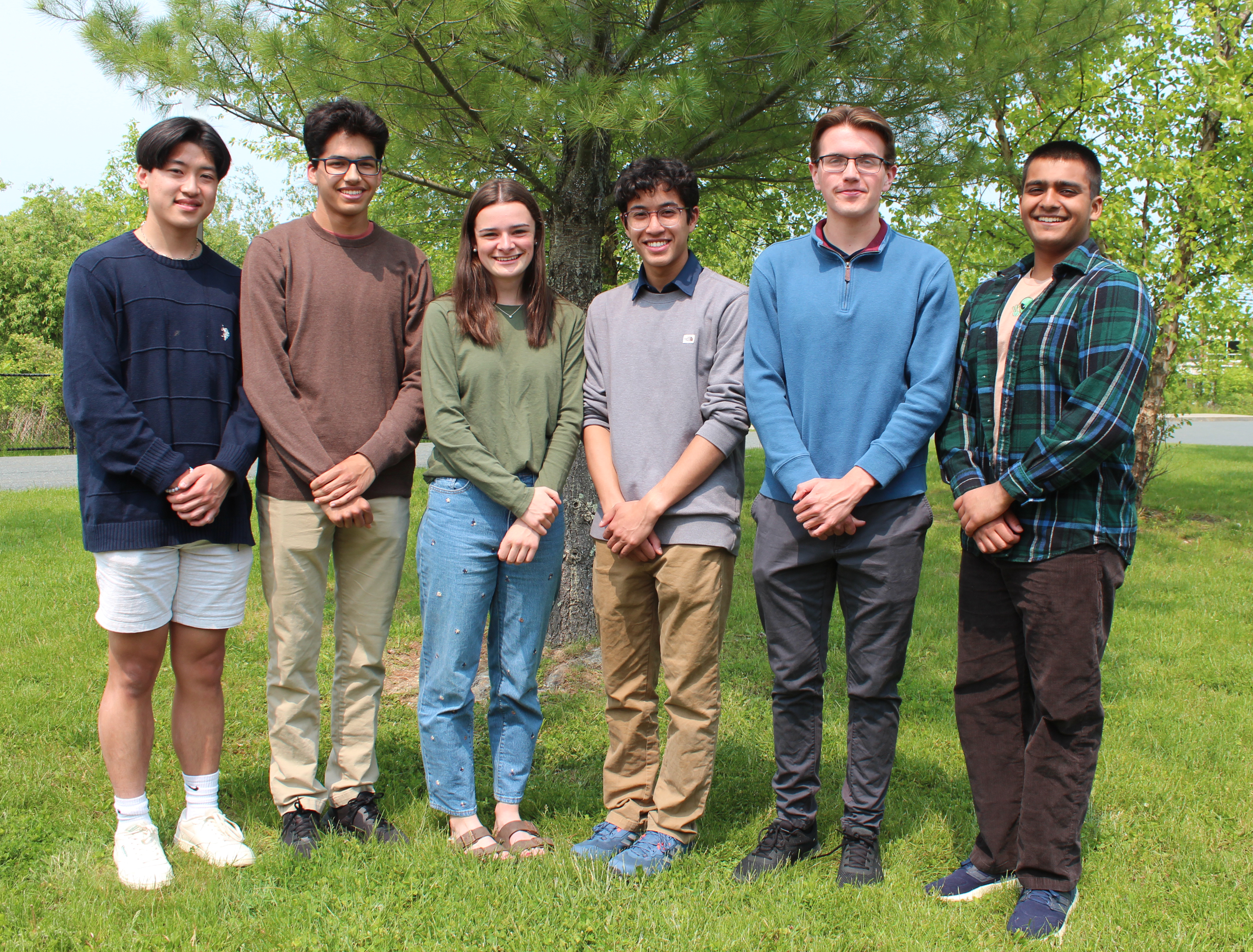 six students pose for photo in front of tree
