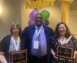 three people pose for photo, two holding plaques