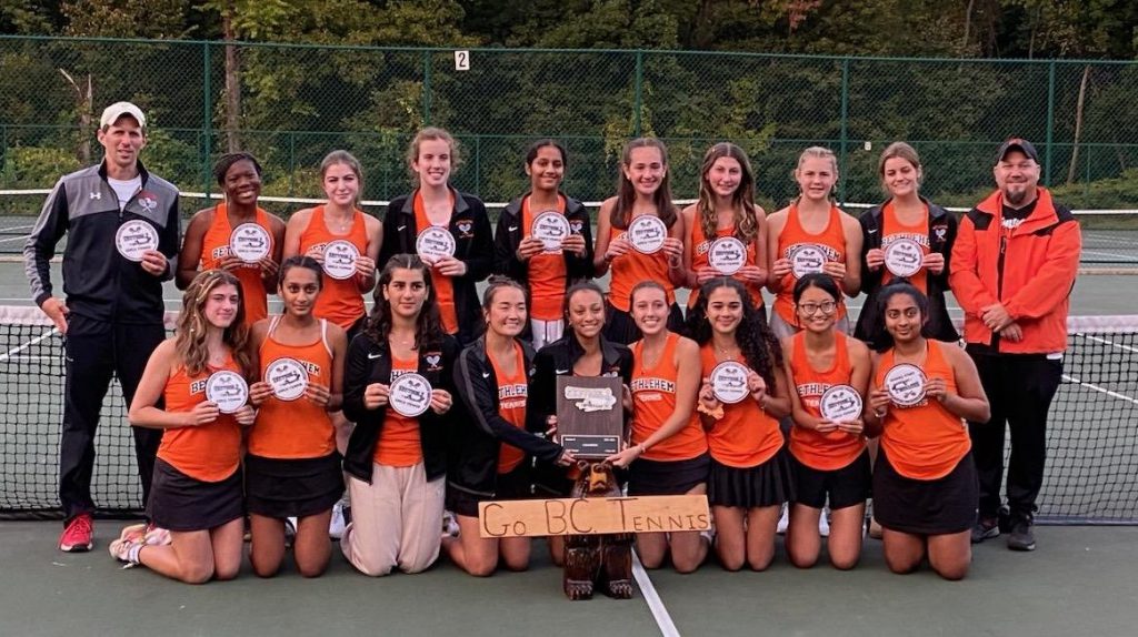 group of students pose with plaque on tennis court