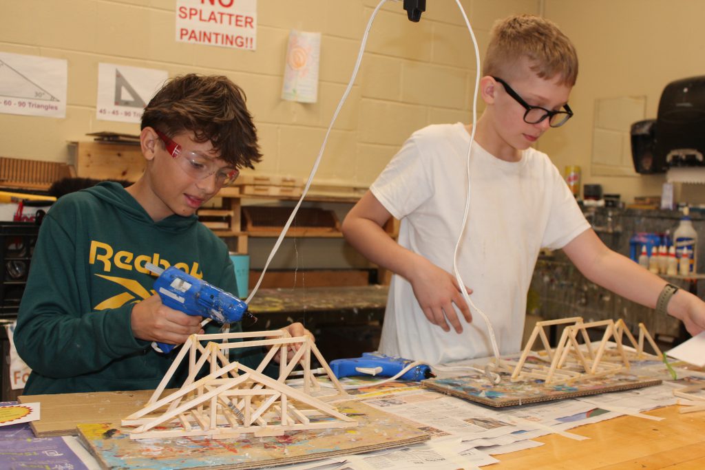 two students build bridges with wood sticks