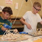 two students build bridges with wood sticks