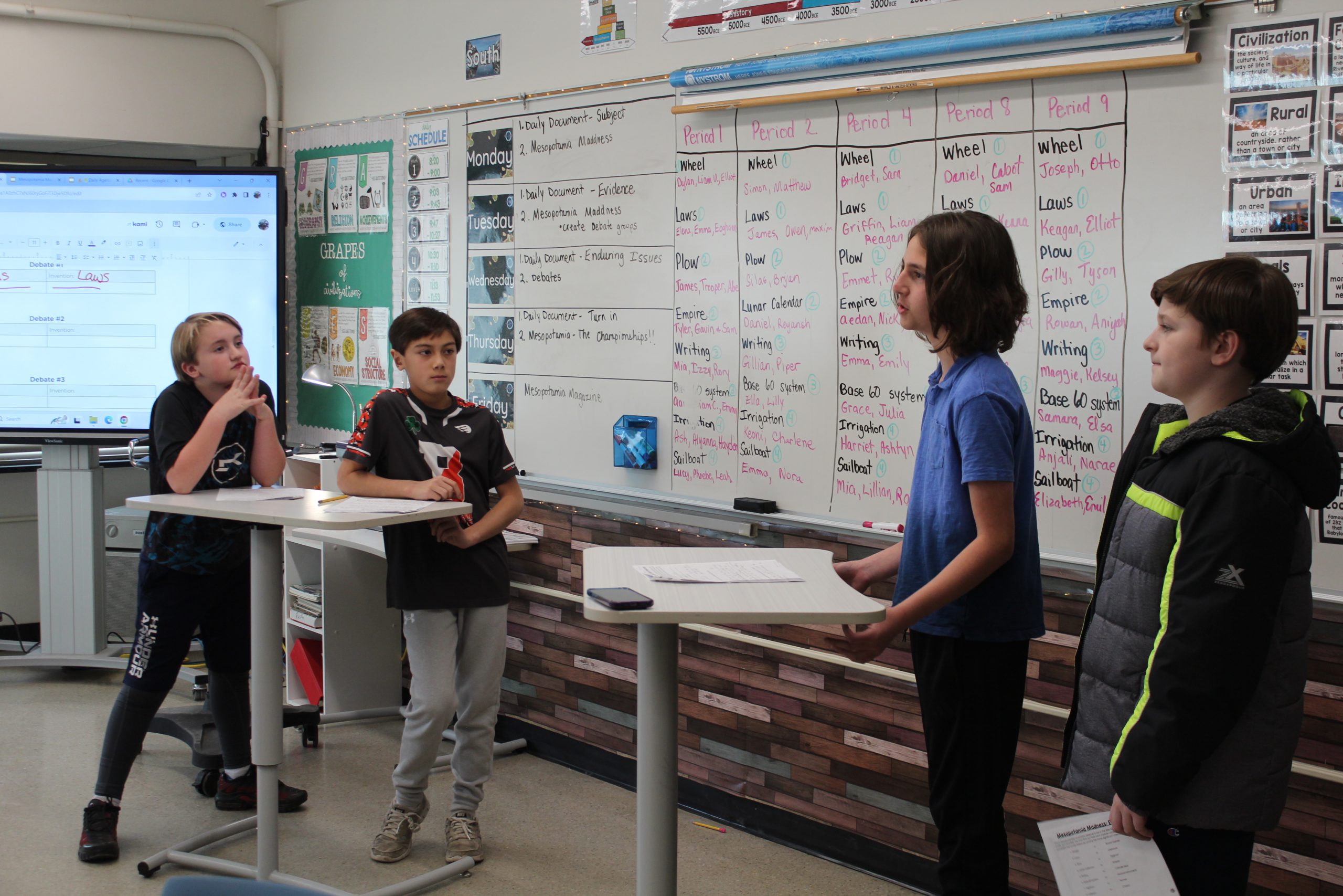 four students standing at front of classroom