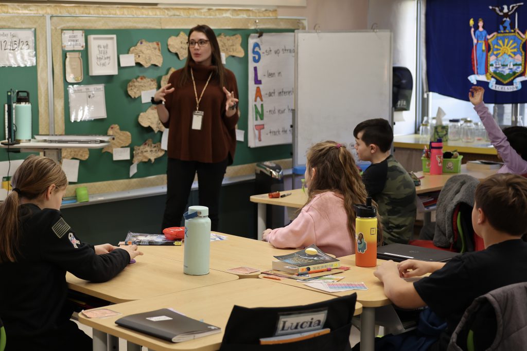 teacher talks to students in front of classroom