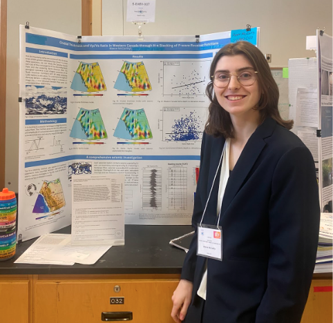 student stands in front of tri-fold display