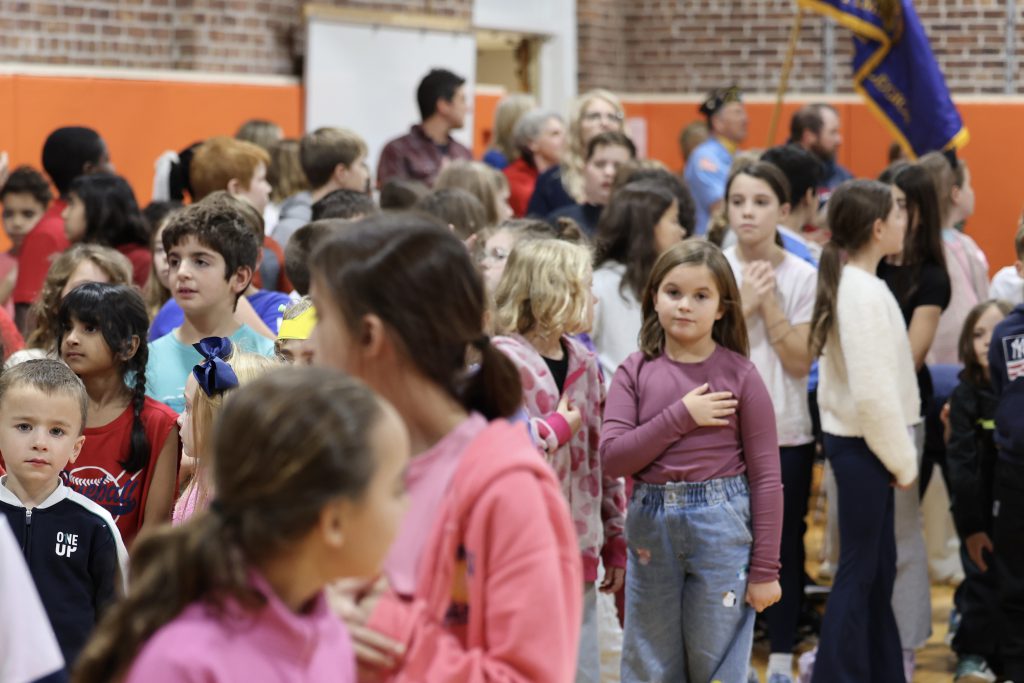 student in crowd with hand over heart
