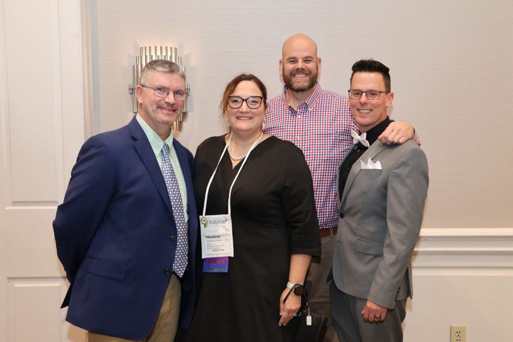 four people pose for photo at event