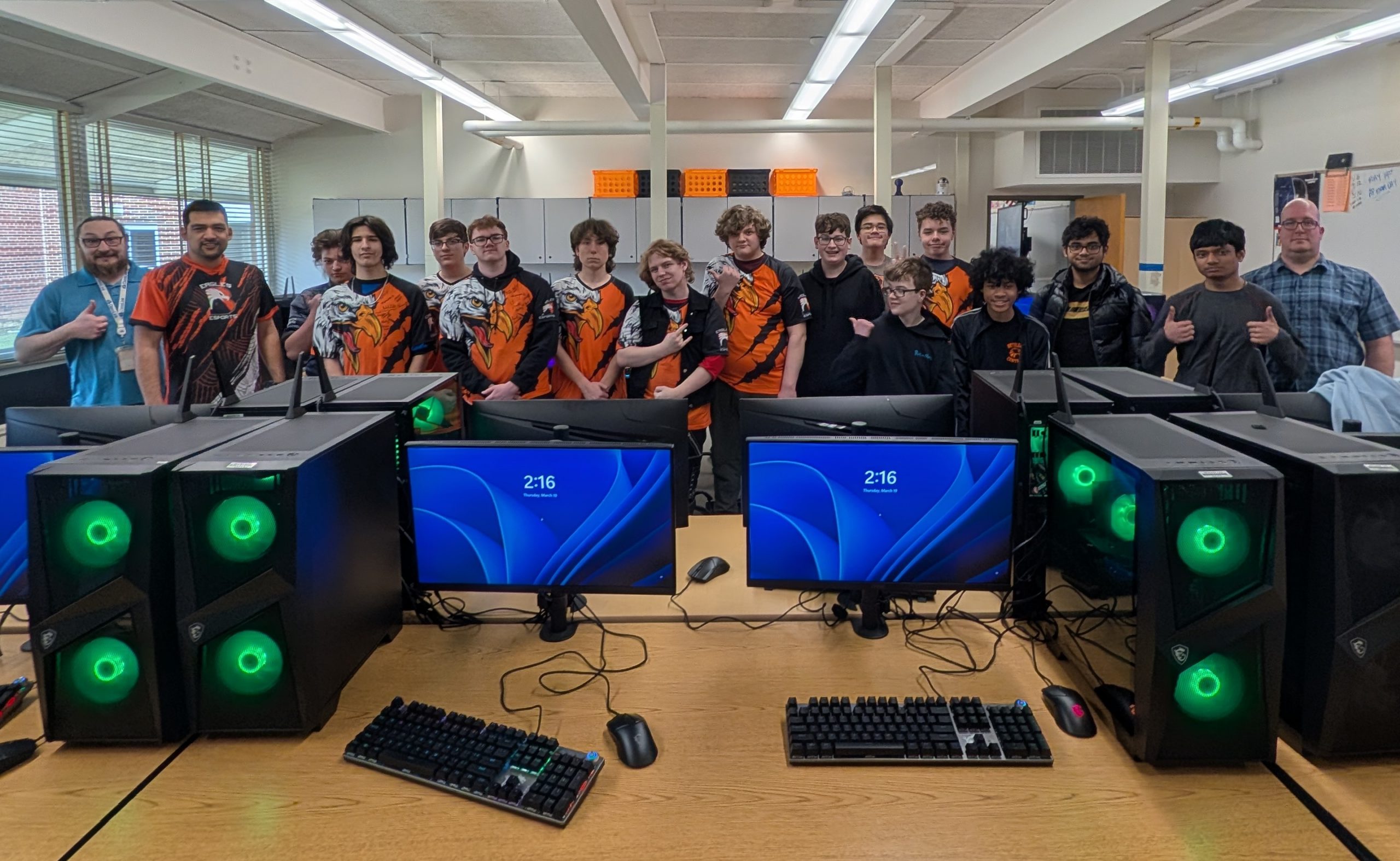 students and staff pose in front of computers