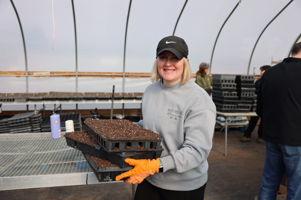 person moving trays of dirt