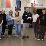 group of people pose for photo holding checks
