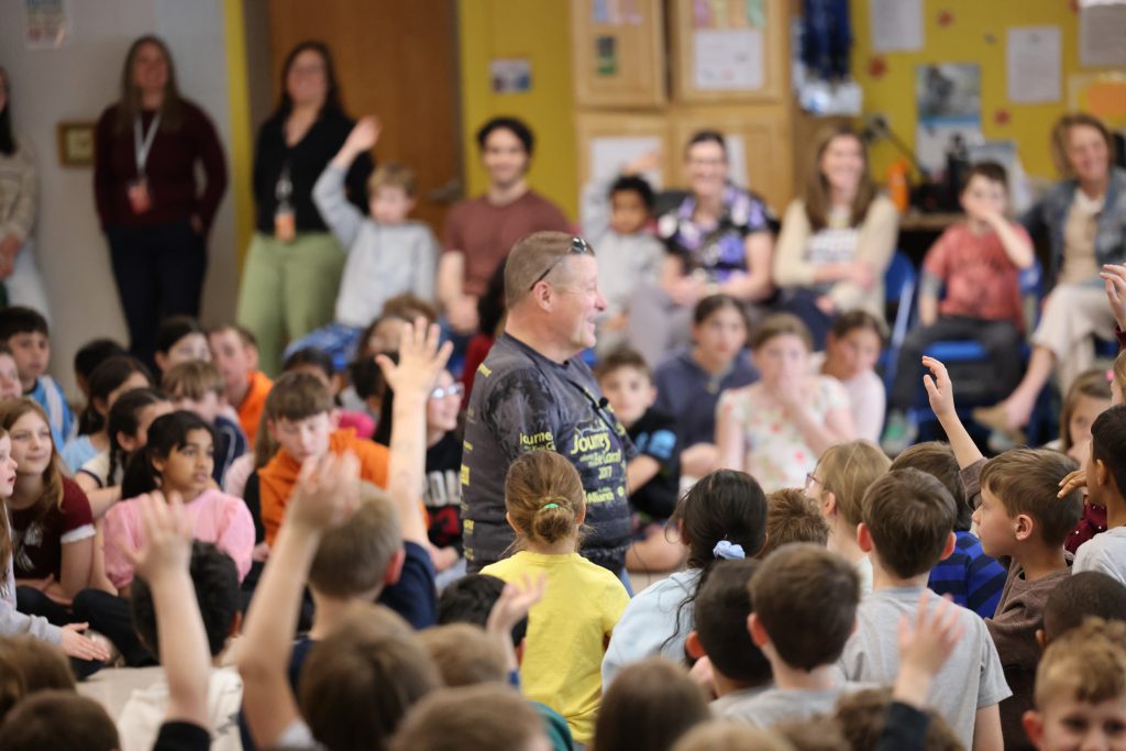 person surrounded by students raising their hands