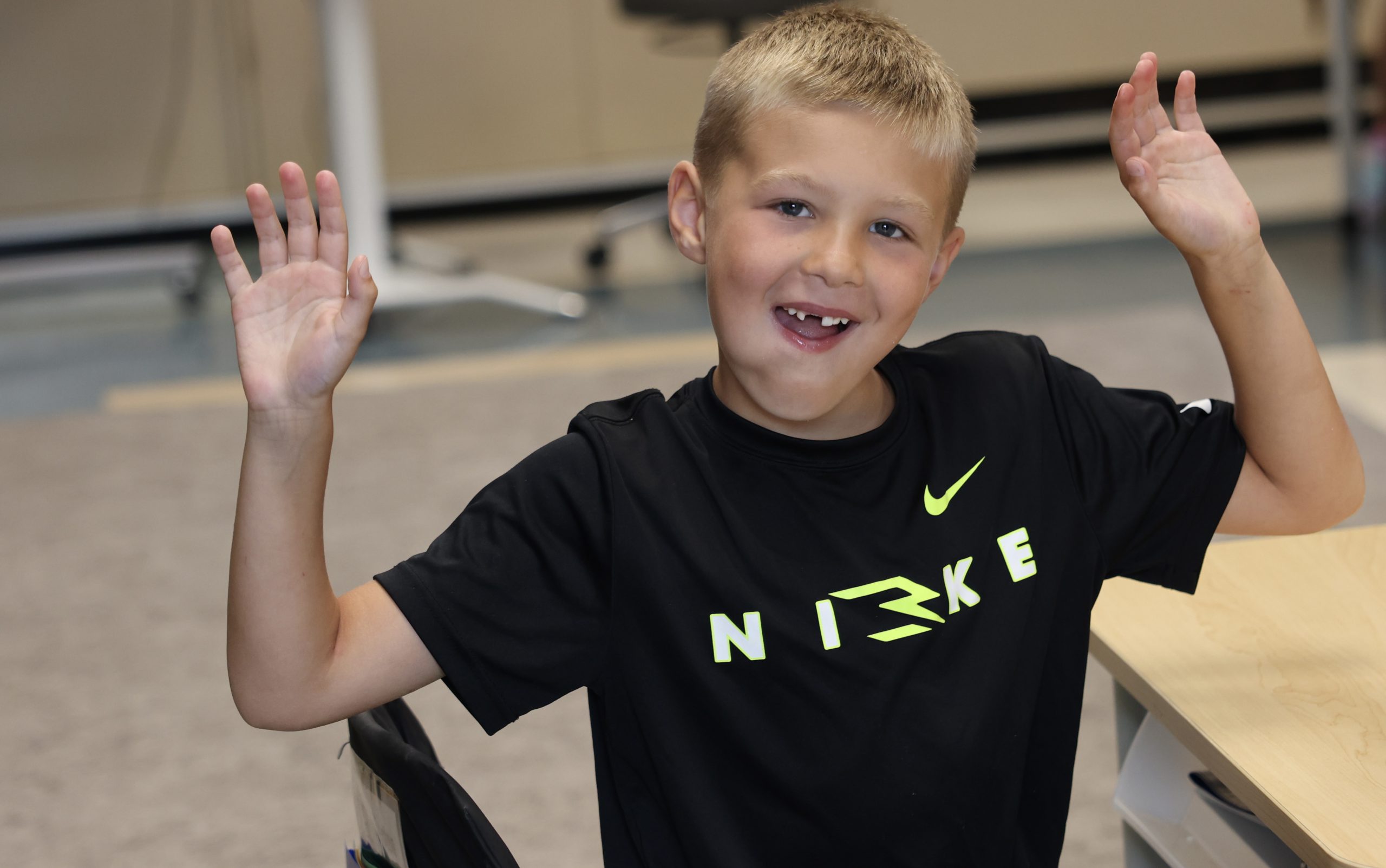 student with hands raised, smiling