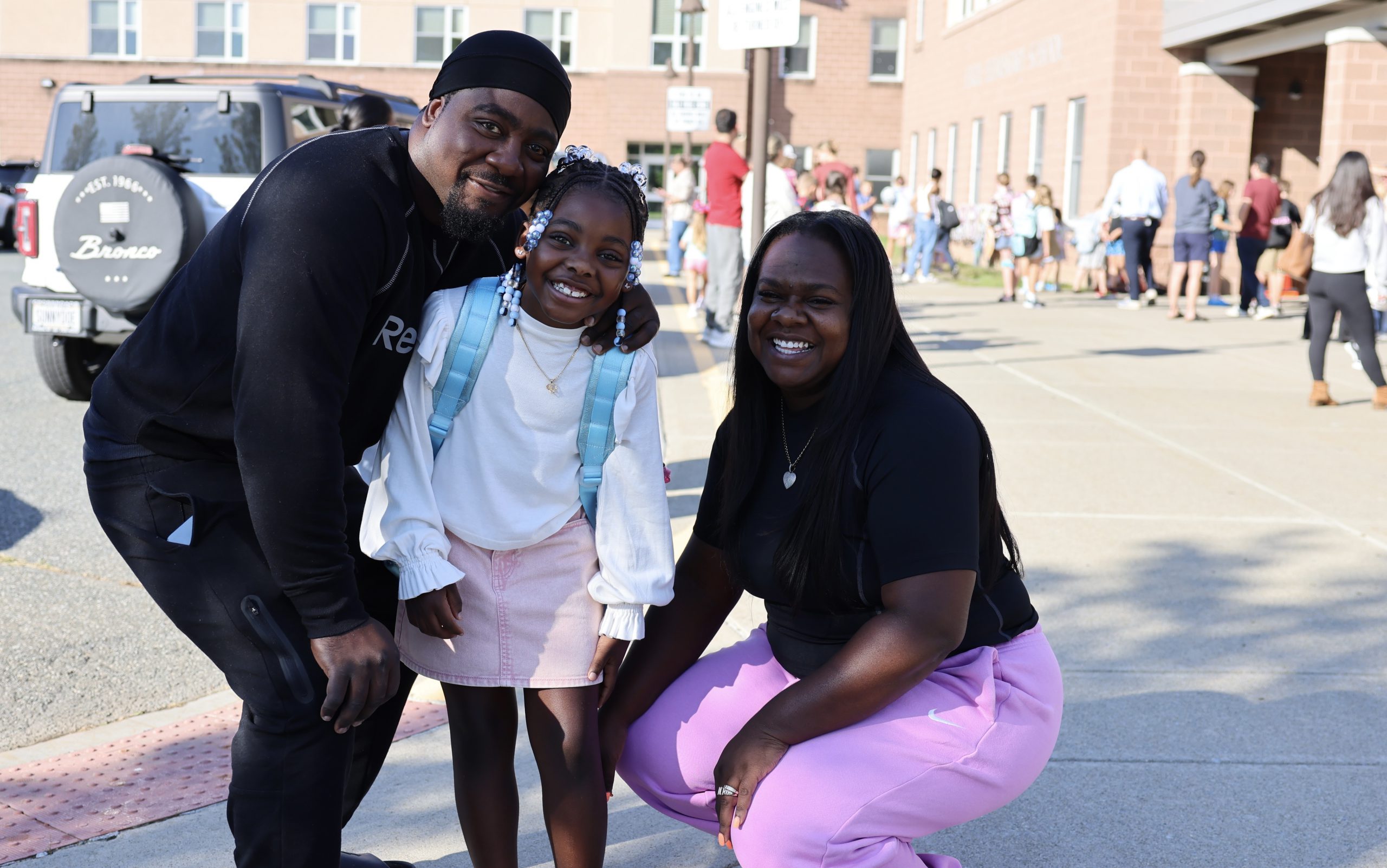 family poses for photo in front of school