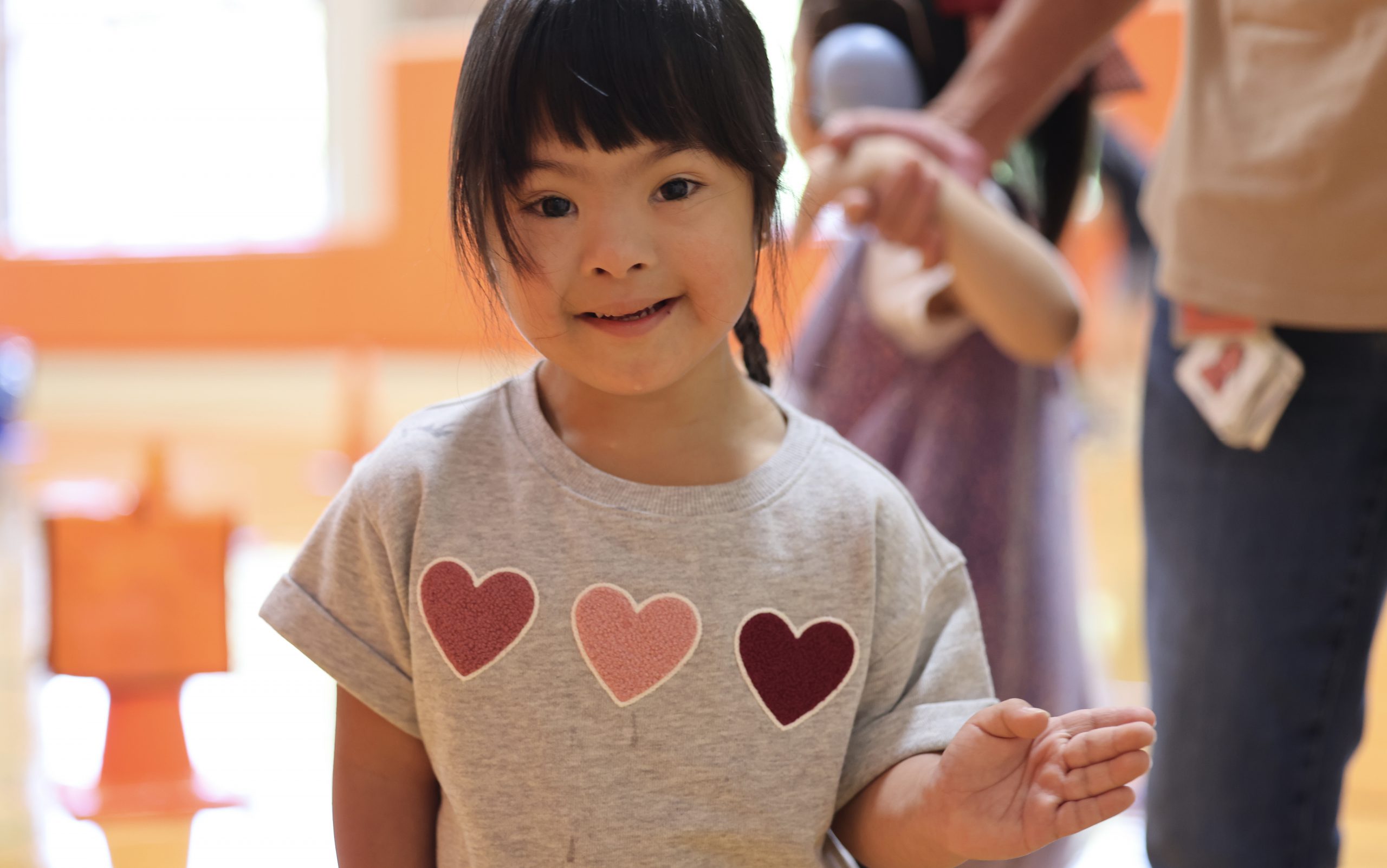student wearing heart tshirt, waving